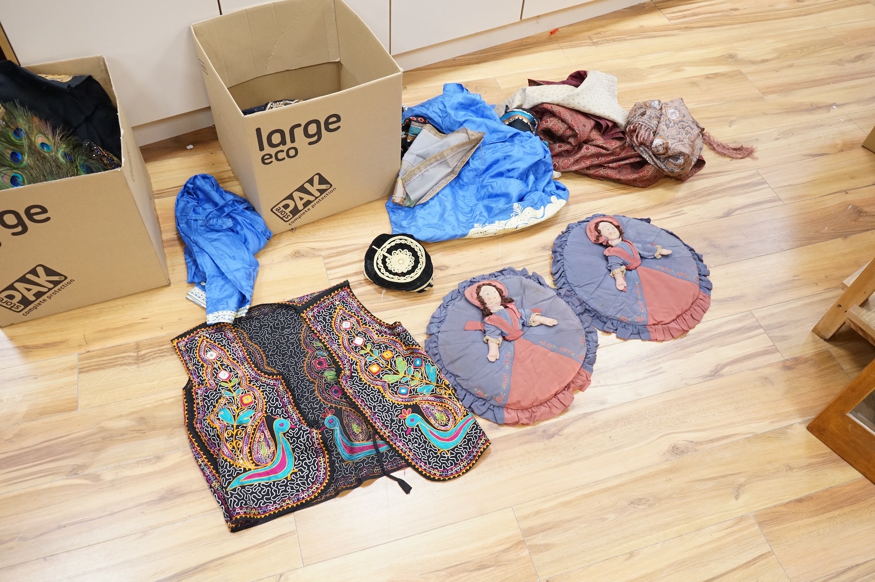 A quantity of mostly 20th century Middle Eastern and Indian woven and printed textiles and a peacock feather fan (2 boxes).